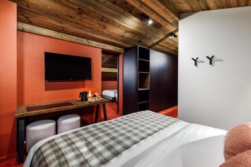a bedroom with a bed and a flat screen tv at Hôtel Névé in Morzine