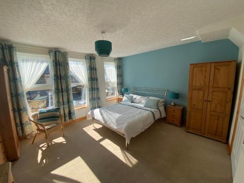 1 dormitorio con 1 cama, 1 silla y ventanas en Felltop Cottage, en Keswick