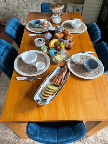- une table en bois avec des aliments pour le petit-déjeuner dans l'établissement Le Doux Refuge, à Esquay-sur-Seulles