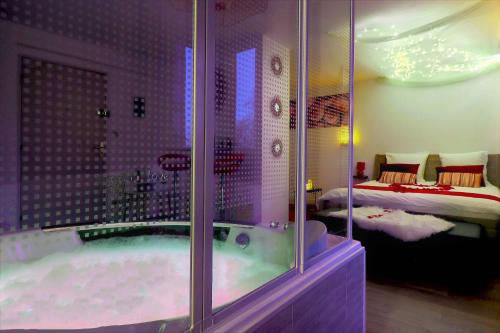 a bathroom with a tub and a bedroom with a bed at Nuit Romantique avec Jacuzzi à 15 min de Toulouse in Blagnac