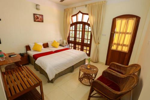 ein Schlafzimmer mit einem Bett, einem Stuhl und einem Fenster in der Unterkunft The Sanctum Spring Beach Resort in Varkala