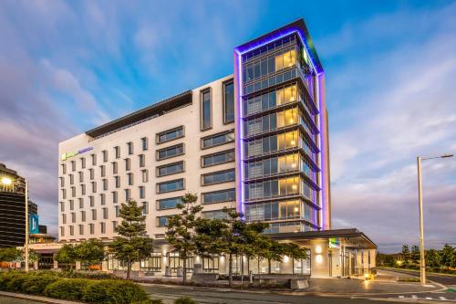 un edificio blanco alto con luces moradas. en Holiday Inn Express & Suites Sunshine Coast, an IHG Hotel, en Maroochydore