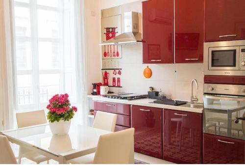 una cocina con armarios rojos y una mesa con un jarrón de flores en casa vacanze L'Altra Diaz, en Siracusa
