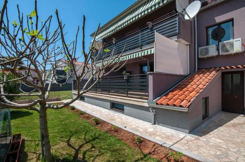 a building with a tree in front of it at Apartments Kajfes in Fažana