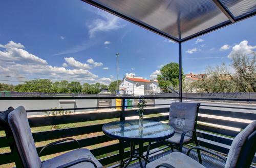 a table with chairs and an umbrella on a balcony at Apartments Kajfes in Fažana