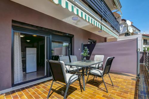 a dining table and chairs on a patio at Apartments Kajfes in Fažana