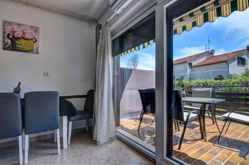 una puerta corredera de cristal que da a un patio con mesa y sillas en Apartments Kajfes, en Fažana