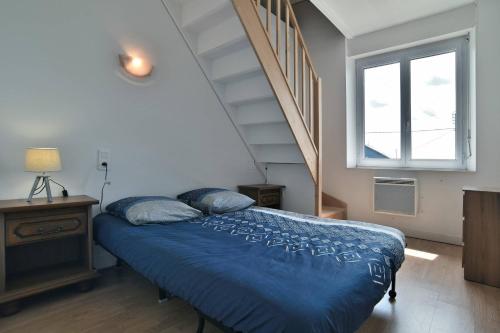 Un dormitorio con una cama azul y una escalera en Maison spacieuse à saint coulomb, en Saint-Coulomb