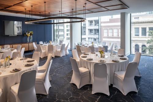 a dining room with white tables and white chairs at voco Auckland City Centre by IHG in Auckland