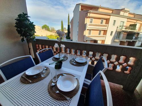 une table avec des assiettes et des serviettes sur un balcon dans l'établissement Le Lavandin - T3 Piscine & Climatisation, à Gréoux-les-Bains