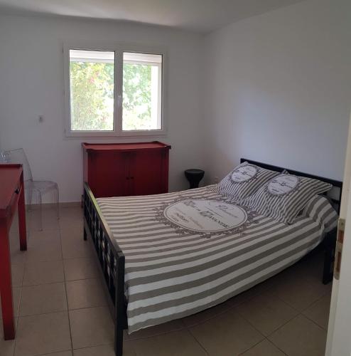 a bedroom with a bed with a striped comforter and a window at Bas de maison de village cosy & relax in Vero