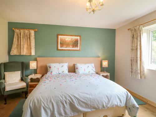 um quarto com uma cama grande e uma cadeira em Orchard Cottage em Derby