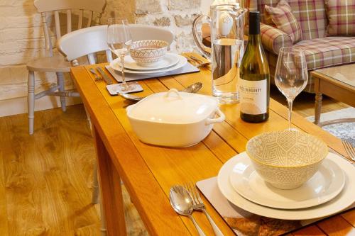 a wooden table with a bottle of wine and glasses at Luxury Barn near Stamford in Wansford