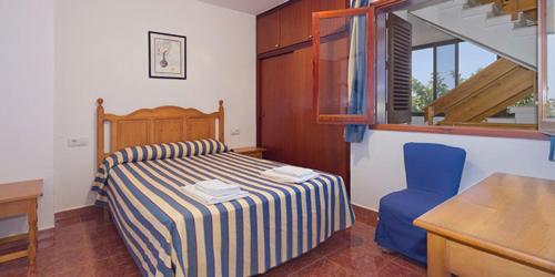 a bedroom with a bed and a blue chair at SOL Y MAR in Cala en Blanes