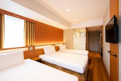 a hotel room with two beds and a flat screen tv at karaksa hotel grande Shin-Osaka Tower in Osaka