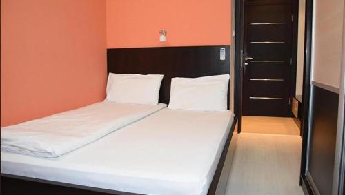 a bed in a room with an orange wall at Motel Park Rogatica in Rogatica