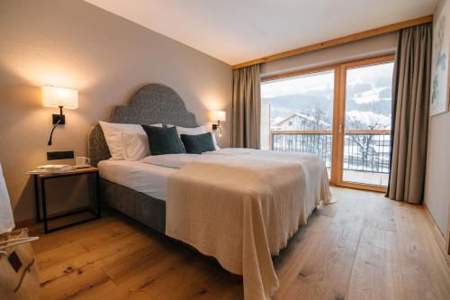 ein Schlafzimmer mit großem Bett und großem Fenster in der Unterkunft Natur Resort RISSBACHER in Stumm