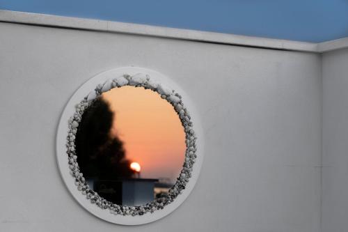 ein kreisförmiger Spiegel an einer Wand mit Sonnenuntergang in der Unterkunft Mbaccimari B&B in Cetraro