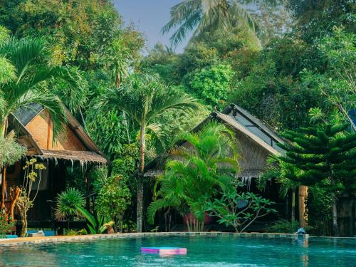 a swimming pool in front of a resort with palm trees at Munchies Bungalows in Koh Phangan