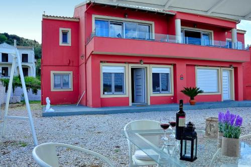 una casa roja con una mesa y sillas frente a ella en Darmanin Αpartment 4 Gyalos Corfu, en Astrakeri