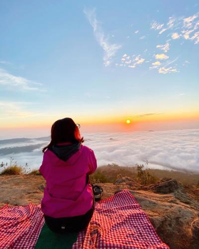 a woman sitting on top of a mountain watching the sunset at D'Yoga Bamboo House in Kintamani