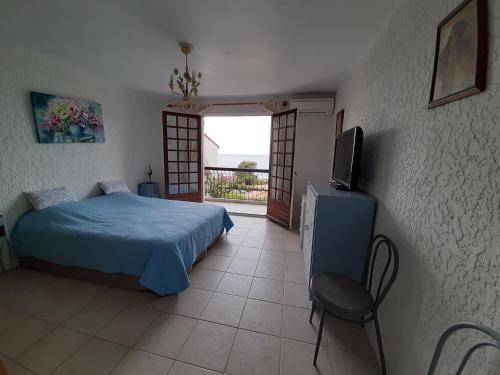 a bedroom with a bed and a tv and a window at Villa mitoyenne, 100m des plages - 3 chambres- in Sagone