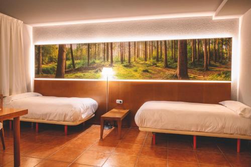 two beds in a room with a painting on the wall at Abba Xalet Suites Hotel in Sispony
