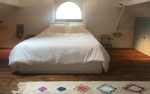 a bedroom with a large white bed with a window at A Côté, c'est aussi chez vous ! in Namur