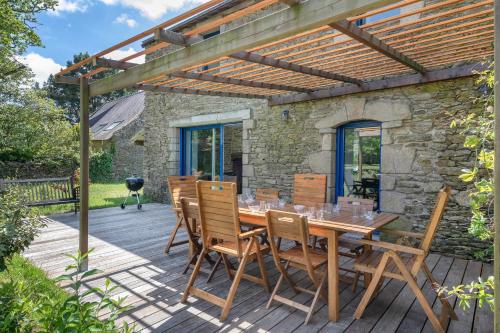 une table et des chaises en bois sur une terrasse en bois dans l'établissement Maison pour 8 personnes à Sarzeau - Superbe jardin, à Sarzeau