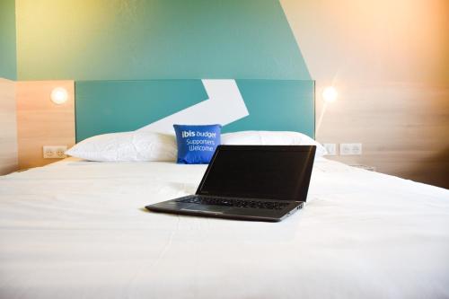 a laptop computer sitting on top of a bed at ibis Budget Millau Viaduc in Millau