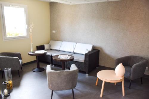 a waiting room with a couch and tables and chairs at ibis Budget Millau Viaduc in Millau