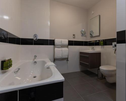 a bathroom with a tub and a toilet and a sink at The Kingsley Hotel in Cork