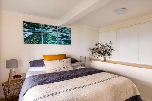 a bedroom with a bed and two paintings on the wall at Y Vue - Beachside Apartment with Ocean Views in Wye River
