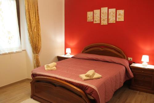 um quarto vermelho com uma cama com duas toalhas em casa vacanze Nonna Nunzia em Bosa