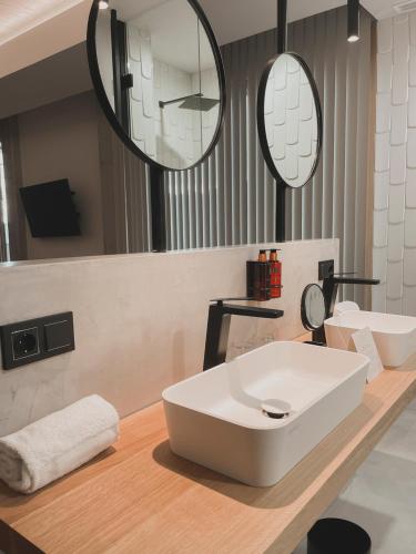 a bathroom with a white sink and two mirrors at Atmos Hotel Boutique in Outes