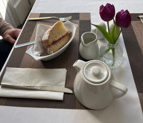 a table with a plate of cake and a teapot at The Tontine Hotel & Bar in Ironbridge