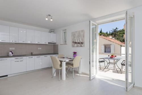 uma cozinha com armários brancos e uma mesa com cadeiras em Apartments Fortinia Dubrovnik- FREE PARKING em Dubrovnik
