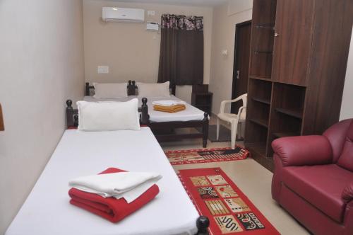 a room with two beds and a red couch at HOTEL TEMPLE CITY in Papanāsam