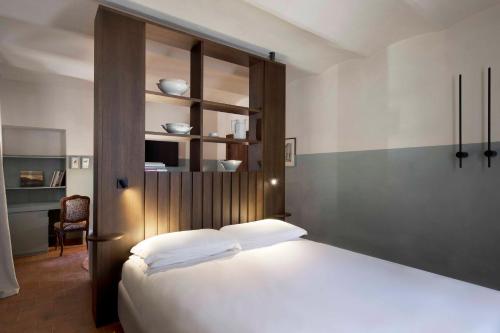 a bedroom with a white bed with a wooden headboard at Cà del Re in Verduno