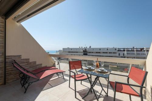 een balkon met een tafel en stoelen en uitzicht op de oceaan bij Village Naturiste - Emotion X Heliopolis sea view in Cap d'Agde