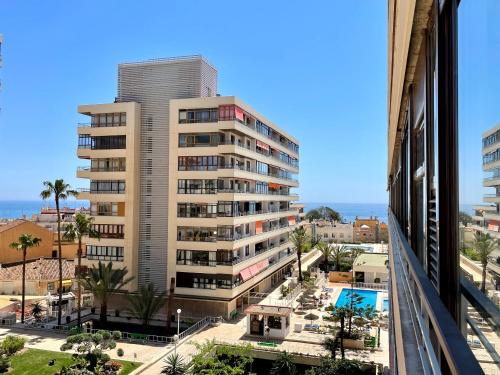 un edificio alto con una piscina delante en Modern Place City & Beachlife in heart of Torremolinos by Solrentspain, en Torremolinos