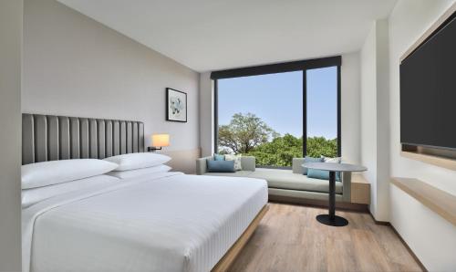 a white bedroom with a large bed and a large window at Fairfield by Marriott Vadodara in Vadodara