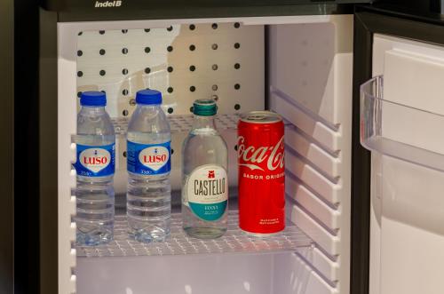 a refrigerator with bottles of water and a can of cocacola at Nicola Rossio Hotel in Lisbon