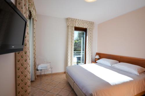 a bedroom with a bed and a flat screen tv at Residence Alle Palme in Riva del Garda