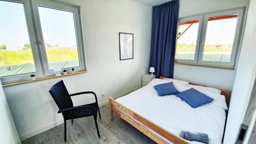 una camera con letto, sedia e finestre di Gąski Dom 100m2 3 sypialnie 2 łazienki 800 m do morza a Gąski