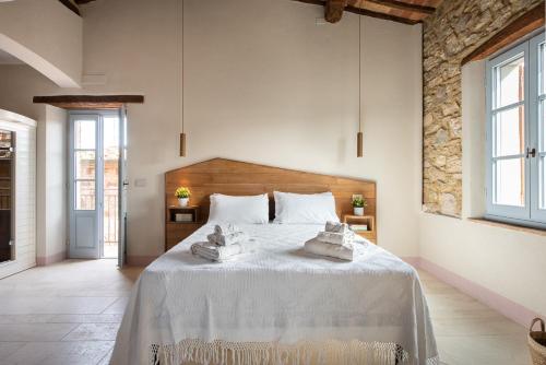 1 dormitorio con 1 cama blanca grande y toallas. en La Casetta di Nise, charming private spa, en Castelnuovo dellʼAbate