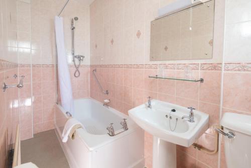 ein Badezimmer mit einem Waschbecken, einer Badewanne und einem WC in der Unterkunft The Crown Hotel in Weymouth