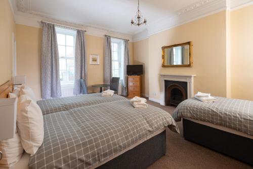 a bedroom with two beds and a fireplace at The Crown Hotel in Weymouth