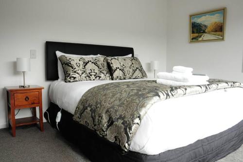 a bedroom with a bed with a black and white comforter at Fergus Hideaway in Te Anau