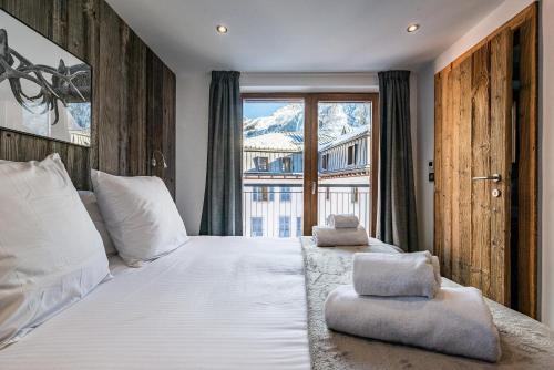une chambre avec un grand lit blanc avec une fenêtre dans l'établissement Le Globe Argentière Chamonix - by EMERALD STAY, à Chamonix-Mont-Blanc